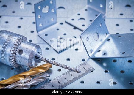 Metalllineal Bohrkronen und Winkelstangen auf perforiertem metallischem Hintergrund. Stockfoto