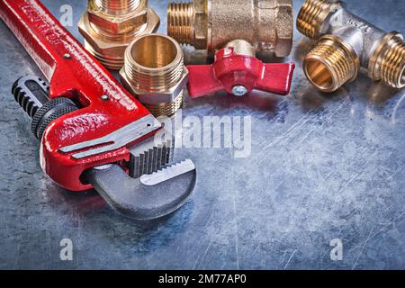 Affenschlüssel Rohrverschraubungen aus Messing Ventil auf metallischem Hintergrund. Stockfoto