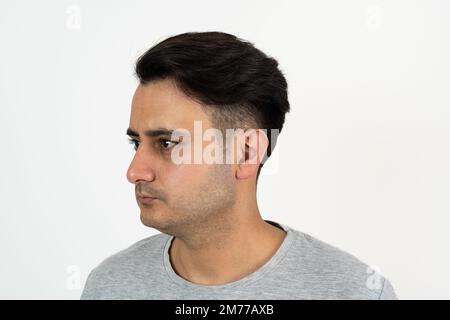 Porträt eines braungehäuteten Mannes mit seidig gepflegtem schwarzem Haar auf isoliertem weißem Hintergrund. Stockfoto