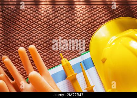 Notizblock Bauhelm Isolierhandschuhe Elektrischer Tester auf dielektrischer Matte. Stockfoto