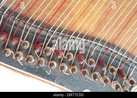 Top-horizontales Studiofoto eines alten Holzzithers isoliert auf weißem Hintergrund. Detail der Schnur-Pins. Staubiges und zerkratztes Musikinstrument. Stockfoto