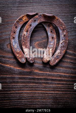 Rostiges, altmodisches Pferdeschuh auf altem dunklen Holzhintergrund, Baukonzept mit Draufsicht. Stockfoto