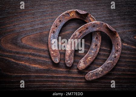 Rostiges, altmodisches Horsehoe auf altmodischem dunklem Holzbrett, Baukonzept. Stockfoto