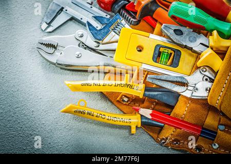 Satz von Bauwerkzeugen im Werkzeuggürtel auf Betonhintergrund. Stockfoto