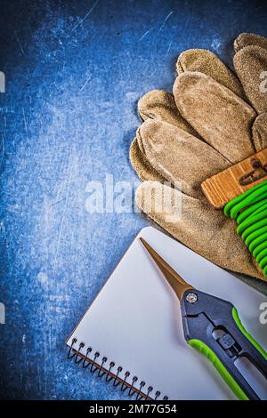 Weicher Drehverschluss Gartenschere Schutzhandschuhe Arbeitsbuch auf metallischem Hintergrund. Stockfoto