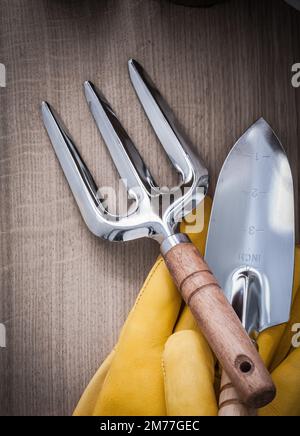 Handschaufelkelle aus Stahl Gartenbau Gabel Sicherheitshandschuhe aus Leder auf Holzhintergrund Nahansicht Landwirtschaftskonzept. Stockfoto