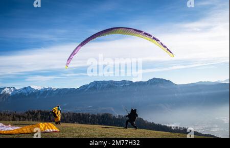 Männer auf einer grasbewachsenen Hanglage bereiten den Gleitschirmflug von Vetriolo Terme, Provinz Trient - Trentino Alto Adige - Paragliding-Schule - Italien vor Stockfoto