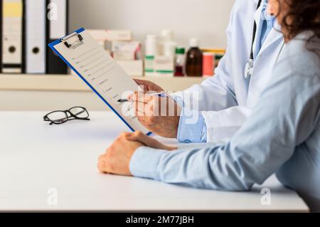 Foto eines selbstbewussten männlichen Arztes, der einem Patienten in einem Krankenhaus während des Tages Testergebnisse zeigt Stockfoto