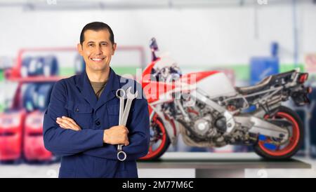 Frontansicht Porträt eines Motorradmechanikers, der sich in einer mechanischen Werkstatt aufstellt und Sie in einem Kopierbereich ansieht Stockfoto