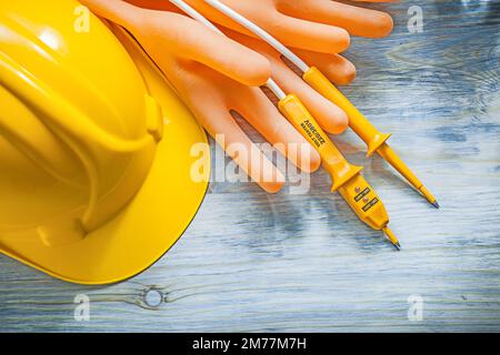 Gelber Schutzbauhelm Elektrotester Dielektrische Handschuhe auf Holzbrettern Stromkonzept. Stockfoto