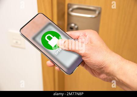 Nahaufnahme einer unbekannten Person, die ein Smartphone benutzt, um die Haustür zu verriegeln – Smart-Home-Technologie. Stockfoto