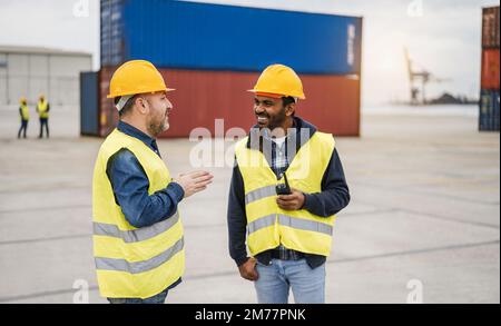 Multiethnische Arbeiter, die Container im industriellen Hafen im Freien kontrollieren - Fokus auf dem linken Männergesicht Stockfoto