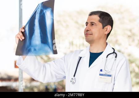 Foto eines jungen männlichen Arztes, der ein Thoraxröntgenbild eines Patienten mit langen Covid im Krankenhaus analysiert. Stockfoto