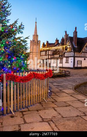 Der kopfsteingepflasterte Marktplatz in Sandbach in Cheshire mit seinem Weihnachtsbaum und Lichtern und dem zenotaph war Memorial und schwarz-weiß Coaching Inn Stockfoto