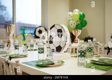 Kinderfußball- oder Fußball-Partytisch mit Plastikbesteck und Süßigkeiten. Festliche Dekoration zum Geburtstag, Boy Party. Geburtstagsgrüße. Stockfoto