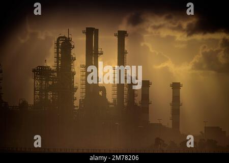 Teil einer großen Ölraffinerie mitten im Smog bei Sonnenuntergang. Foto von 2010. Stockfoto