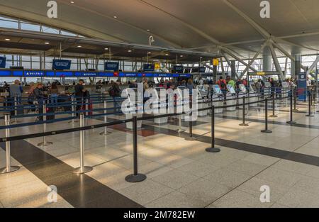 Blick auf den Flughafen von innen mit Check-in-Schaltern der Delta Airline und Personen, die Gepäck einchecken und abgeben. New York. USA Stockfoto