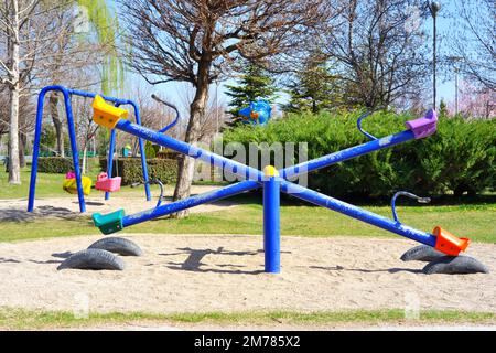 An einem sonnigen Sommertag mit Bäumen im Hintergrund im Park säen und schaukeln Stockfoto