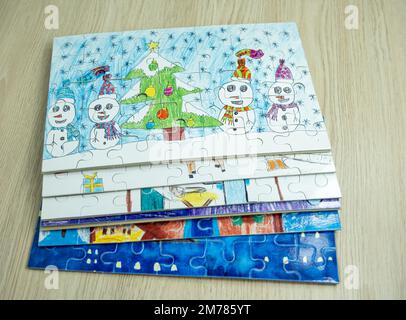 Ein Blick von oben auf Puzzles mit verschiedenen Wintergemälden von Kindern Stockfoto
