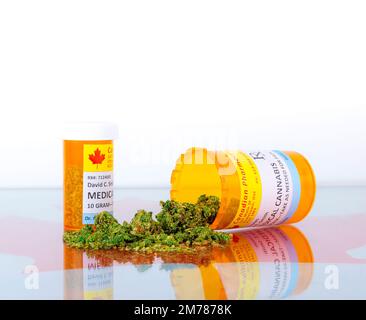 Cannabis in Kanada. Zwei Flaschen für Cannabis auf einem Glastisch mit einem roten Ahornblatt unter dem Glas. Eine Flasche liegt auf der Seite. Stockfoto