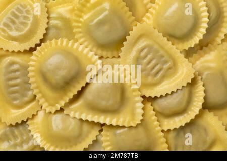 Traditionelle frische italienische Pasta Mezzelune gefüllt mit Mozzarella und Pilzen im Vollformat als Hintergrund Stockfoto