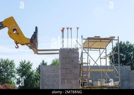 Gabelstapler mit Ausleger entladen Betonblöcke in Paletten, die auf der Baustelle verwendet werden. Stockfoto