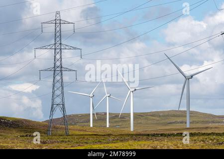 Stromleitungen marschieren über ein schottisches Moor, mit Windturbinen dahinter. Highlands, Schottland, Großbritannien. Stockfoto