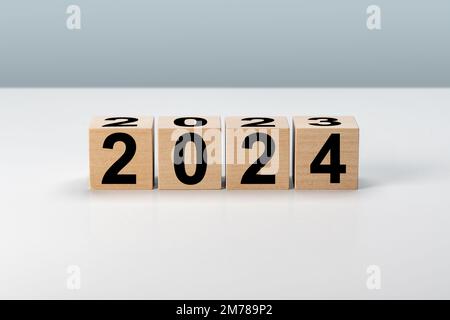 Neujahr 2024. Holzblöcke 2024 auf neutralem grauen Hintergrund. 2023 bis 2024 auf Holzkubus zur Vorbereitung des Neujahrswechsels und zur Eröffnung neuer Geschäfte Stockfoto