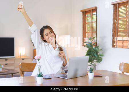 Entspannendes Zeitkonzept, Frau trinkt Kaffee und Arme strecken, nachdem sie müde von der Arbeit im Home Office war. Stockfoto