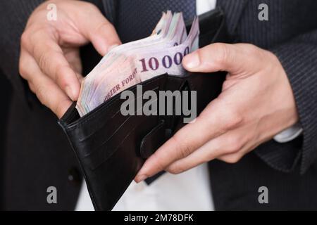 Nahaufnahme von Männerhänden und viel Geld in der Brieftasche. Stockfoto
