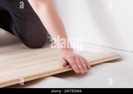 Professioneller Arbeiter, der neue Parkettböden im Innenbereich installiert, Nahaufnahme Stockfoto
