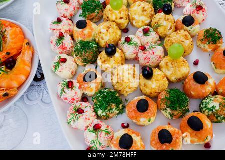 Partyessen, Weihnachtsbaum Kiwis Salat und verschiedene Würstchen Stockfoto