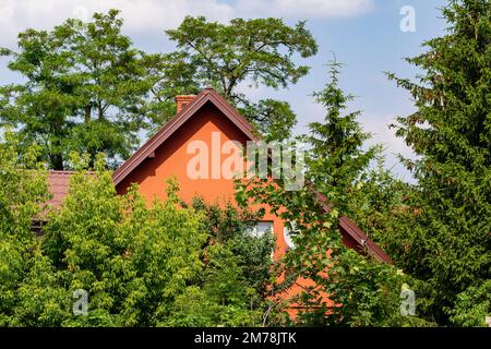 Haus oder Gebäude an einem sonnigen Tag verdeckt von grünen Bäumen. Sommer. Stockfoto