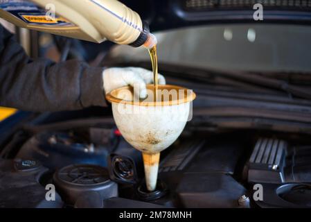 Arbeiten in einer Garage, Arbeiter kontrollieren und wechseln das Motoröl Stockfoto