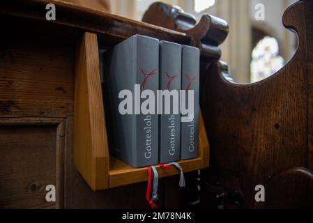 Ein deutsches Hymne-Buch, das hinter einer Bank in einer Kirche steht Stockfoto