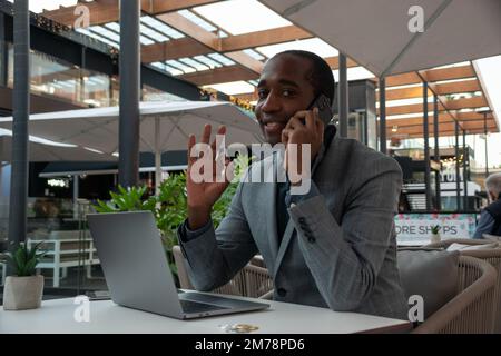 Ein junger Händler während eines Telefonats zeigt an, dass alles in Ordnung ist Stockfoto