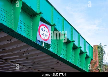 Grün lackierte Eisenbrücke mit Schild mit Höhenbeschränkung Stockfoto