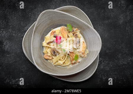 Pasta mit Käse, Huhn und Pilzen, im Dunkeln Stockfoto