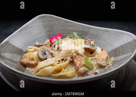 Pasta mit Käse, Huhn und Pilzen, im Dunkeln Stockfoto