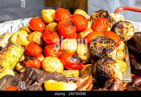 Leckere gebackene Grillkartoffeln, Tomaten und Fleisch in einer Pfanne Stockfoto