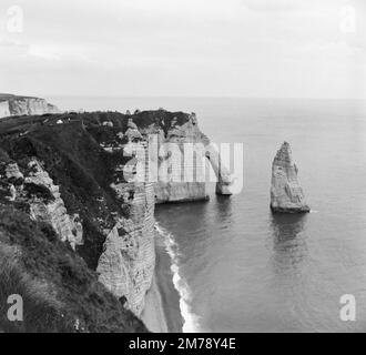 Chalk Cliffs, Natural Arch and the Needle oder L'Aiguille an der Küste der Etretat Normandy France c1960. Klassisches Schwarzweiß- oder Schwarzweißbild. Stockfoto