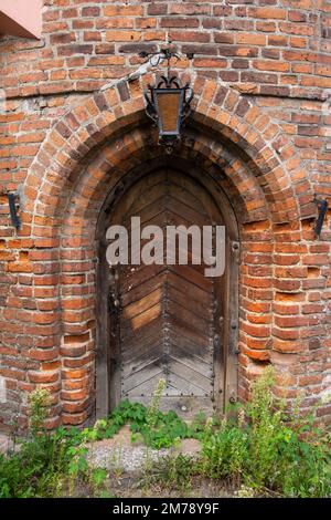 Eingang zu einem historischen Backsteingebäude mit einer hängenden Laterne über der Tür. Wand. Stockfoto