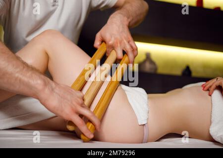Beinmassage mit Bambusstäbchen für eine Frau Stockfoto