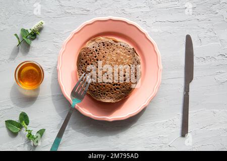 Leckere hausgemachte Schokoladen-Pfannkuchen mit frischen Pfirsichen und Honig, Blick von oben. Stockfoto