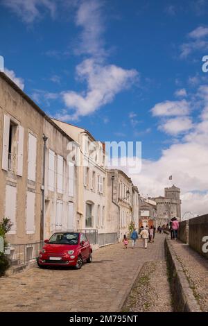 Das rote Auto steht auf einer gepflasterten Straße in einer Gegend, die von Touristen aus der französischen Hafenstadt La Rochelle besucht wird. Stockfoto