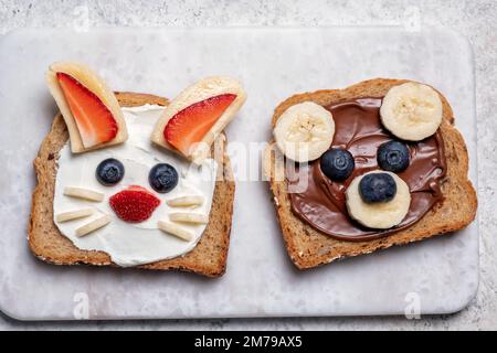 Lustige Tier Gesichter Toasts mit Spreads, Butter, Banane, Erdbeere und Heidelbeere Stockfoto