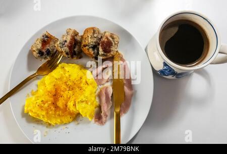 Rührei und Schinken mit schwarzem Kaffee und Blaubeermuffins Stockfoto