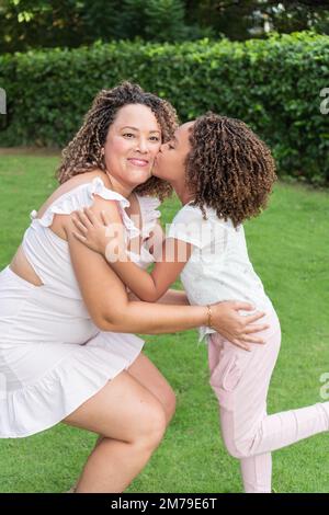 Ein Mädchen küsst seine Mutter auf die Wange im Freien Stockfoto