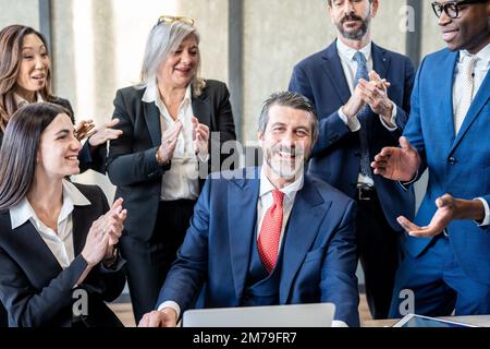 Gruppe multiethnischer Mitarbeiter, die dem Chef nach einem Gespräch über Finanzinvestitionen applaudieren – Business-Team klatscht nach Erfolgen Stockfoto