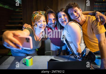 Eine lächelnde Gruppe von Freunden, die während einer Live-Übertragung Selfie nach Radio-Podcast machen Stockfoto